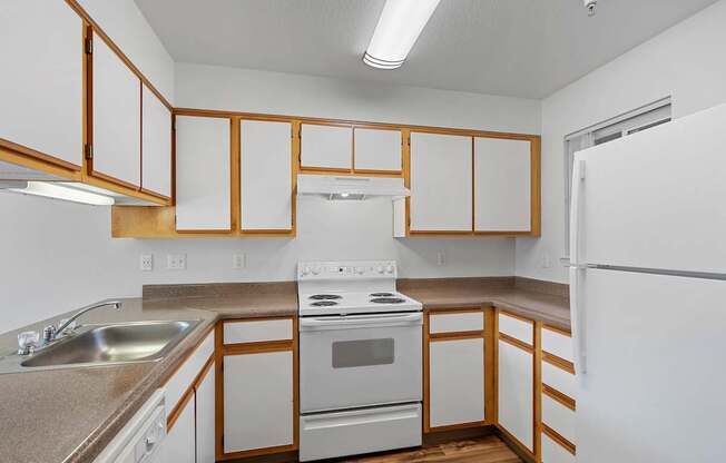 an empty kitchen with white appliances and wooden cabinets