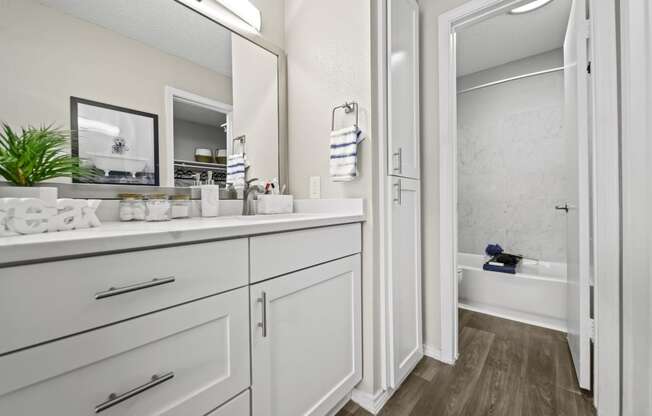 a bathroom with white cabinets and a white bathtub