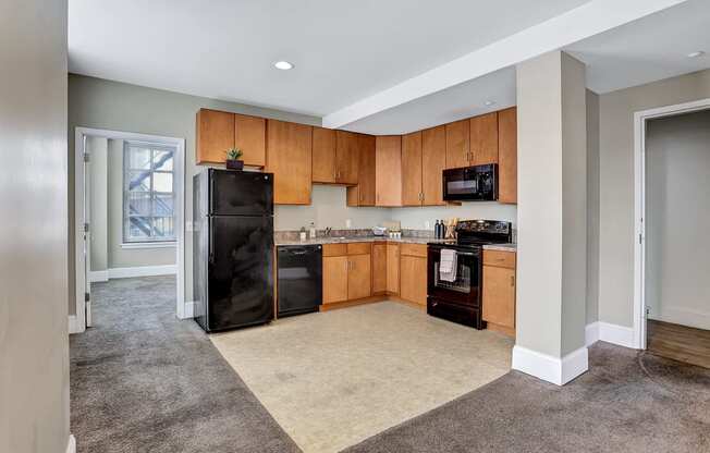 an empty kitchen with wooden cabinets and a black refrigerator