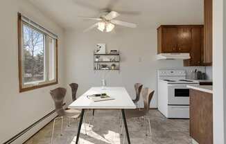 a kitchen with white appliances and a white dining table with four chairs