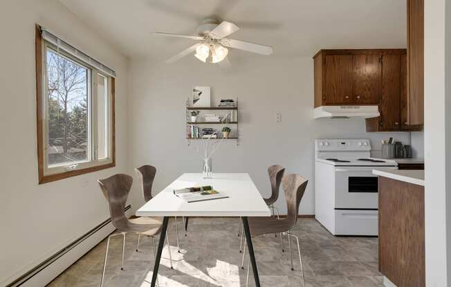 a kitchen with white appliances and a white dining table with four chairs