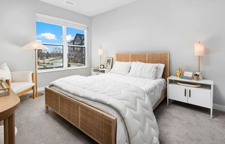 A bedroom with a large bed and a window overlooking a house.