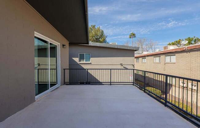 A patio with a black railing and a concrete floor.