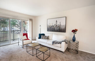 a living room with a white couch and chairs and a balcony at The Glendale Residence, Lanham
