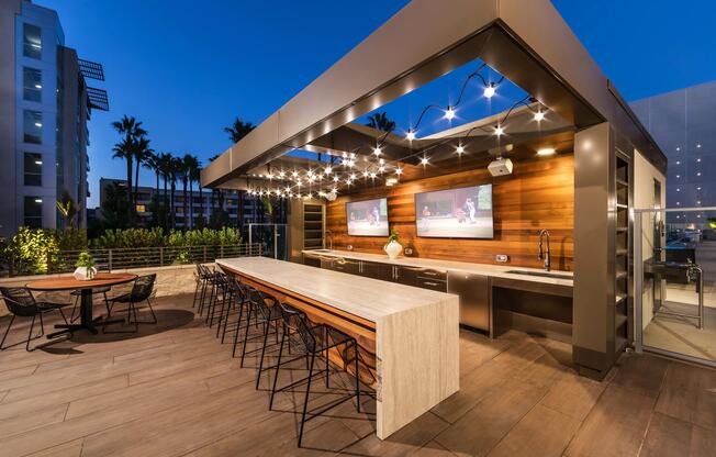 Upscale bar seating and TVs for open‑air dining.