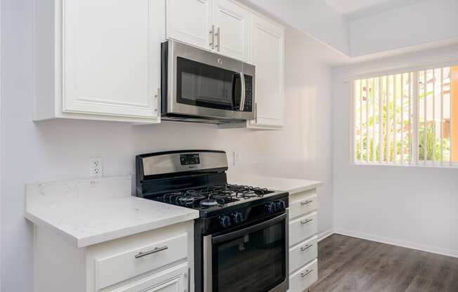 a kitchen with white cabinets and black appliances and a microwave