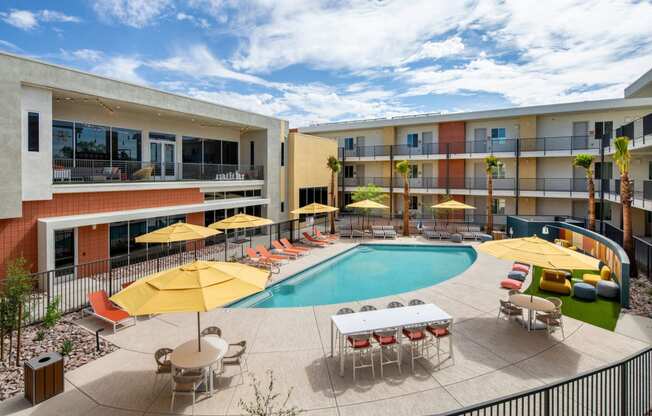 a swimming pool with yellow umbrellas and red and white chairs