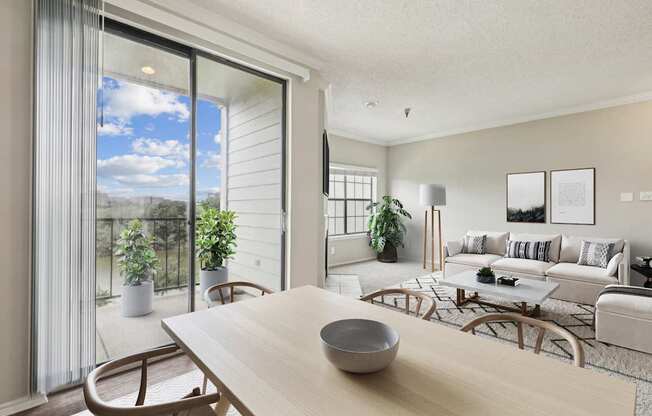 A modern living room  in the A2 floorplan with a wooden table and chairs and a glass sliding door leading to the balcony at Jefferson Creek Apartments in Irving, TX