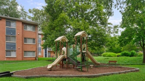 a playground in a yard in front of an apartment building