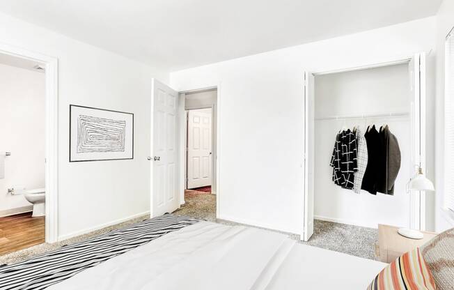 Model Bedroom with En Suite Bathroom,  Open Closet Next to Bed and Framed Wall Art