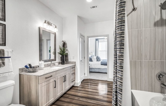 A bathroom with a white toilet, a wooden vanity, and a shower with a curtain.