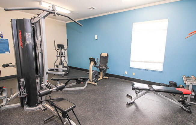 a room with a lot of exercise equipment and a window