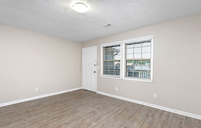 an empty living room with a window and a door