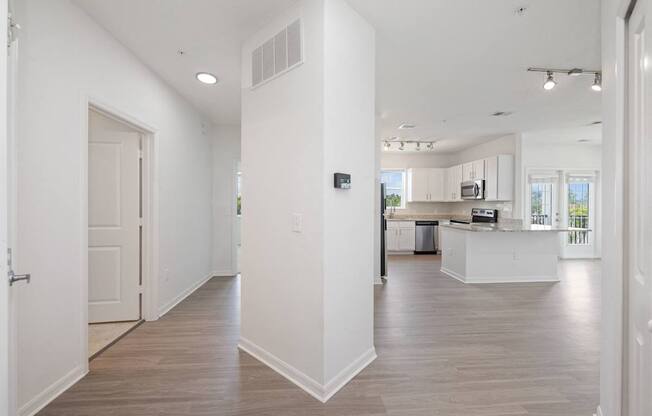 A spacious, empty room with light wood flooring and white walls.