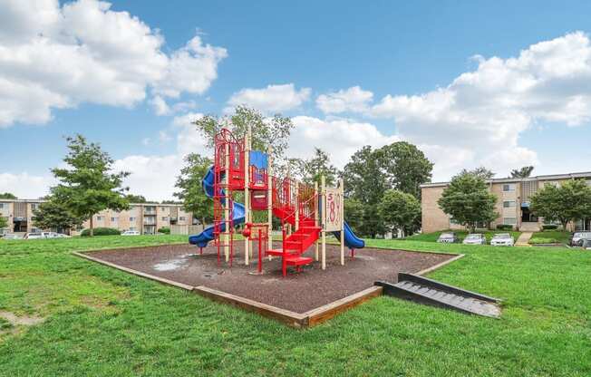 a playground with a set of red slides and a blue slide