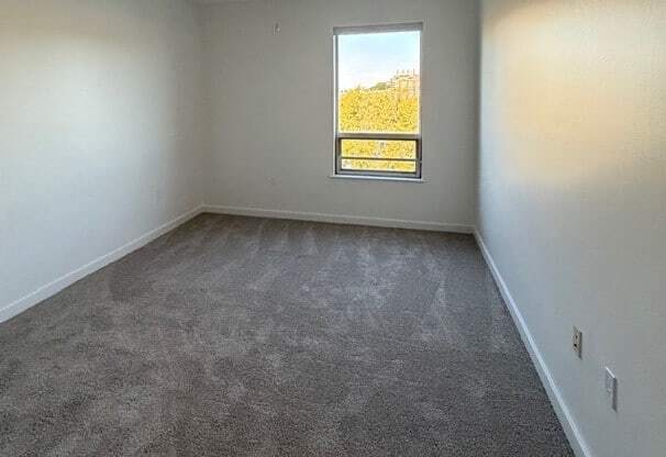 A room with a ceiling fan and a window showing a view of a field.
