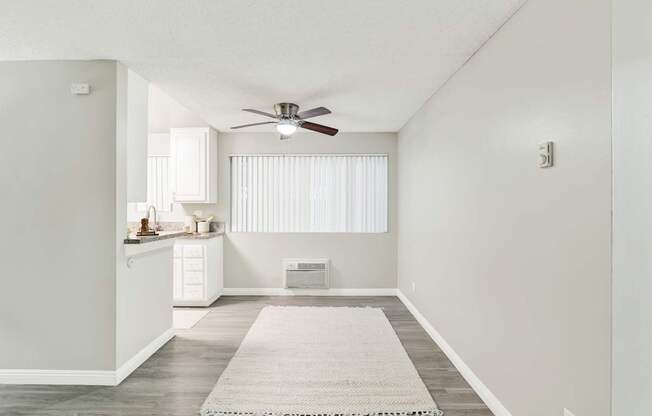 A room with a ceiling fan and a rug on the floor.