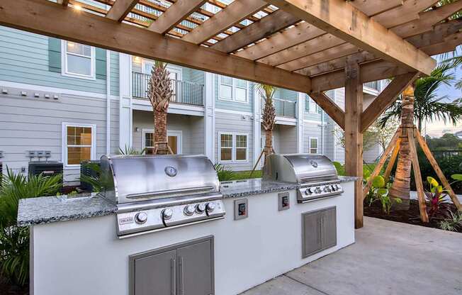 A white outdoor kitchen with a grill and sink.