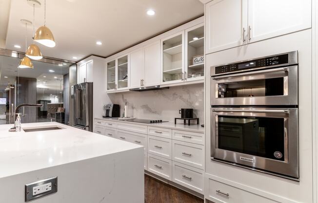 a white kitchen with stainless steel appliances and white counter tops