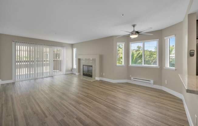 an empty living room with a fireplace and a ceiling fan