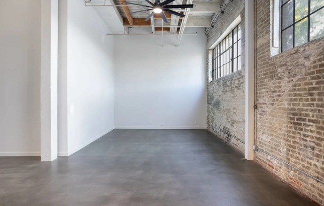 an empty room with a brick wall and a cement floor