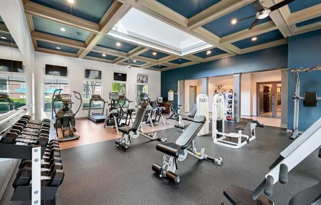 a gym with cardio equipment and weights in a building with blue ceilings