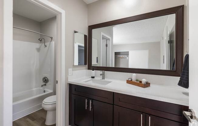 A bathroom with a white sink and a brown mirror.