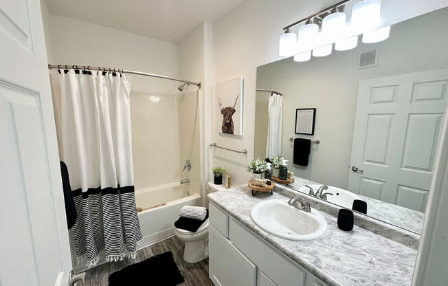A bathroom with a white shower curtain and a white toilet.