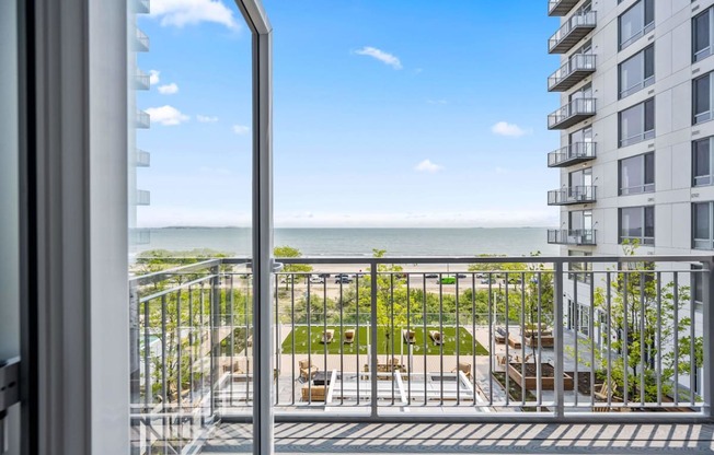 A balcony with a view of the ocean and a building in the distance.