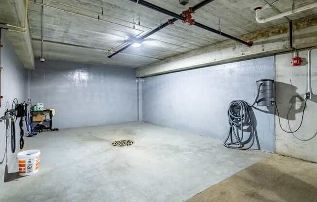 A concrete basement with a concrete floor, walls, and ceiling, with a concrete drain in the middle of the floor.