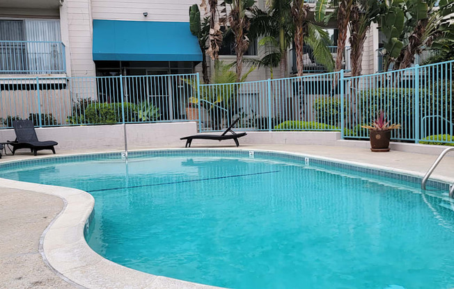 Gated swimming pool and sun deck in lush suroundings at La Mesa Village Apartments in La Mesa, California.