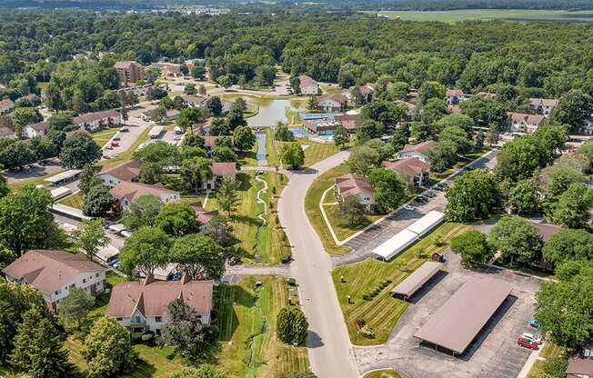 A bird's eye view of a residential area with houses, a swimming pool, and a parking lot.
