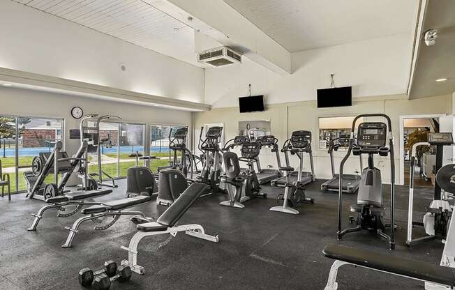 A gym with a variety of equipment including treadmills, weights, and exercise machines.