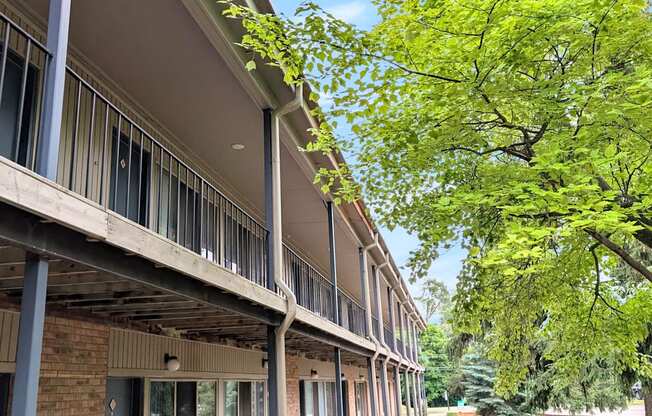 A row of apartment buildings with balconies and trees in the background.