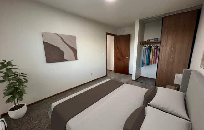 A room with a bed, a plant, and a painting on the wall.