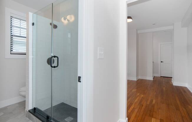 a bathroom with a glass shower and a wooden floor