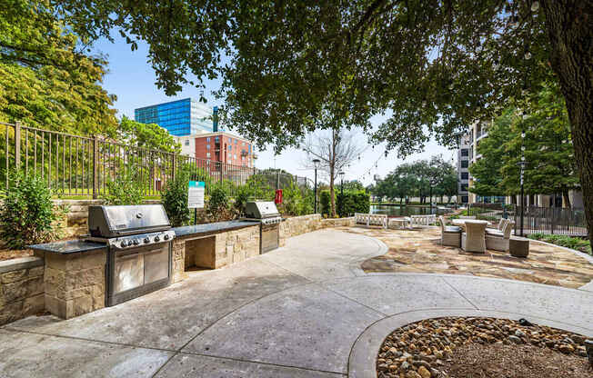 A park with a stone wall and a grill.