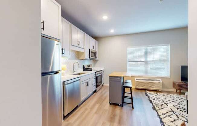 A modern kitchen with stainless steel appliances and wooden flooring.