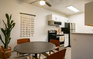 a dining area with a table and chairs and a kitchen in the background