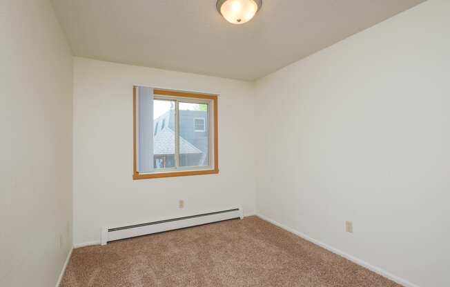 an empty living room with carpet and a window. Fargo, ND Country Club Apartments.