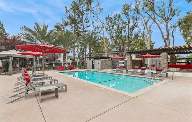 A pool area with red umbrellas and lounge chairs.