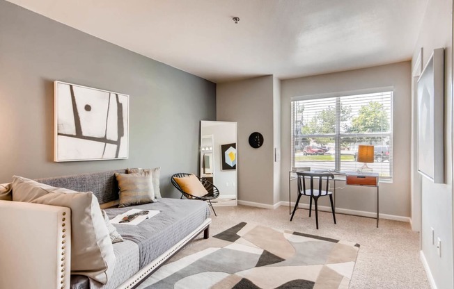 a living room with a couch and a desk and a window