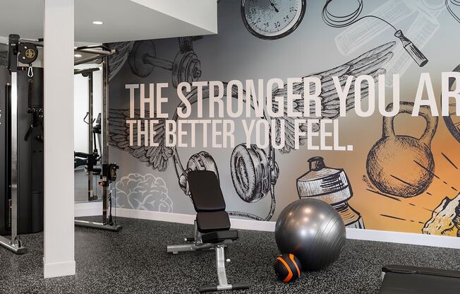 a fitness room with a gym chair and a wall with a motivational quote on it