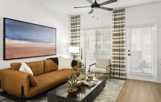 A living room with a brown couch, a coffee table, and a painting on the wall.