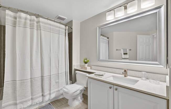 A white bathroom with a toilet, sink, and shower curtain.