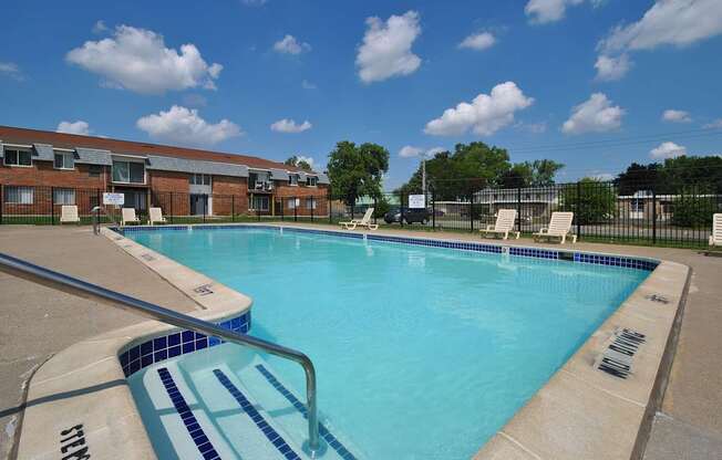 Outdoor swimming pool with sunchairs at Warren Woods Apartments in Warren, MI.