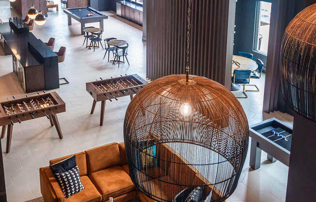 a room with a large bird cage hanging from the ceiling and a lobby with furniture