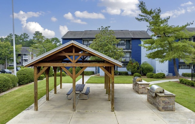 an outdoor pavilion with grills in front of anson at north hills apartments in raleigh nc