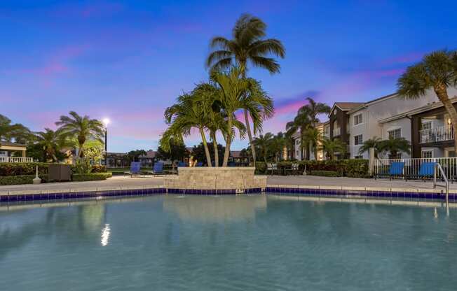 a large swimming pool with palm trees in front of a building