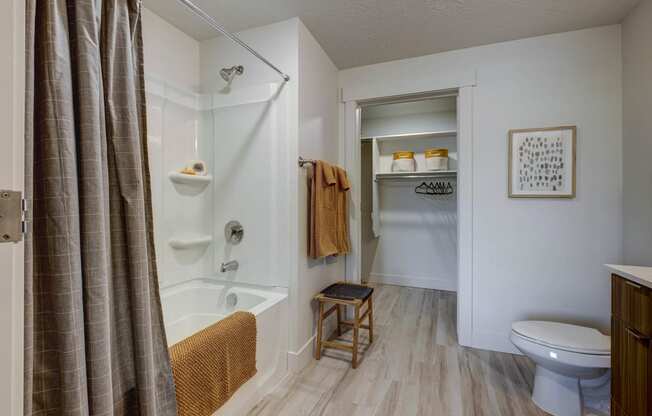 Bathroom with tan décor accents, tub, and storage closet